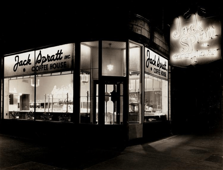 A night time view of the Jack Spratt coffee shop lit from within.